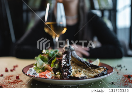 female eat salad with baked eggplant and sauce or drink wine in restaurant female eat salad with baked eggplant and sauce or drink wine in restaurant 131735526