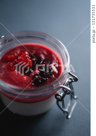 berry panna cotta dessert with cherry sauce in glass jar on black background 131735531