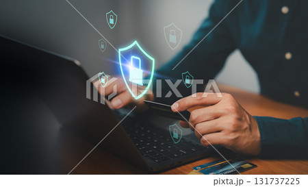 Person holding credit card and typing on laptop with shield and padlock icons. Concept of cybersecurity, secure online payment, data protection, internet banking, fraud prevention and digital safety. Person holding credit card and typing on laptop with shield and padlock icons. Concept of cybersecurity, secure online payment, data protection, internet banking, fraud prevention and digital safety. 131737225