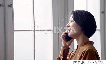 窓辺で電話をしている女性 131738444