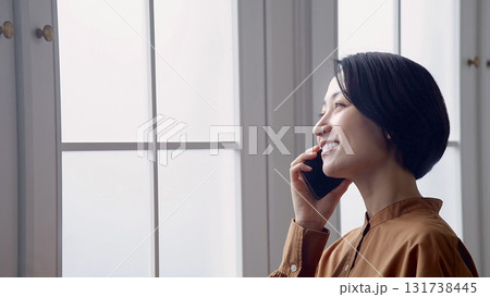 窓辺で電話をしている女性 131738445