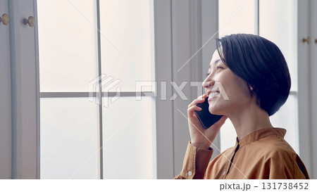 窓辺で電話をしている女性 窓辺で電話をしている女性 131738452