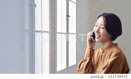 窓辺で電話をしている女性 窓辺で電話をしている女性 131738455