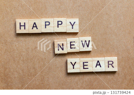 Wooden letter tiles arranged to spell HAPPY NEW YEAR on a brown textured background Wooden letter tiles arranged to spell HAPPY NEW YEAR on a brown textured background 131739424