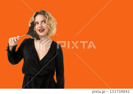 Woman smiles while holding a bat-shaped decoration for Halloween Woman smiles while holding a bat-shaped decoration for Halloween 131739842