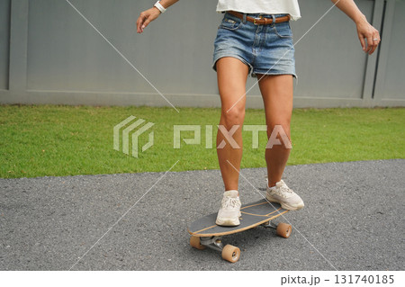 A young woman is skillfully riding a skateboard down a scenic park 131740185