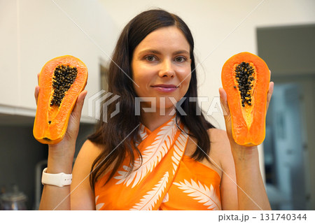 Young woman cuts and peels papaya on the cutting board Young woman cuts and peels papaya on the cutting board 131740344