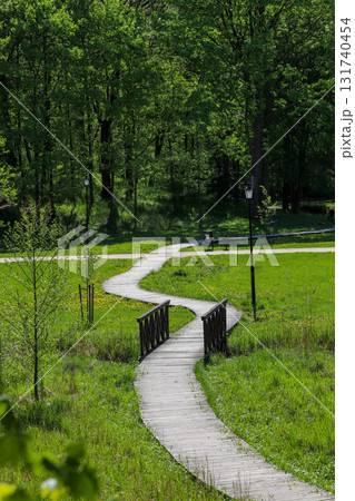 Wooden Walkway Through Lush Green Park Wooden Walkway Through Lush Green Park 131740454