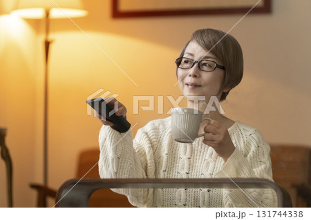 夜にリビングでリモコンを使いテレビを見るシニア女性 夜にリビングでリモコンを使いテレビを見るシニア女性 131744338