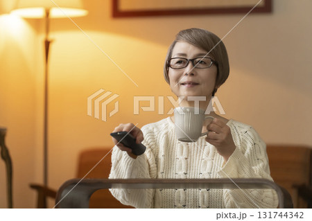 夜にリビングでリモコンを使いテレビを見るシニア女性 夜にリビングでリモコンを使いテレビを見るシニア女性 131744342