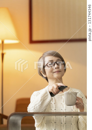 夜にリビングでリモコンを使いテレビを見るシニア女性 131744346