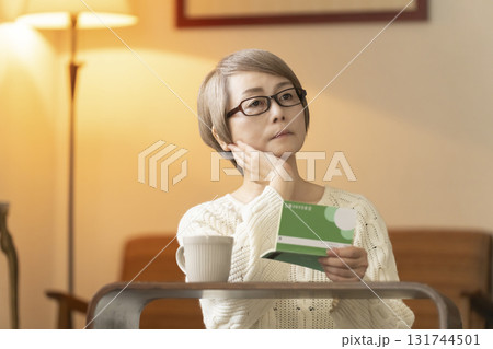 夜にリビングで通帳を見るシニア女性 131744501
