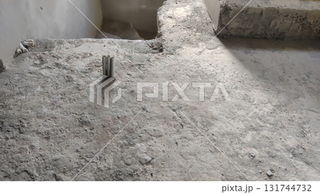 Close up of a concrete floor with metal pipes and a concrete structure above Close up of a concrete floor with metal pipes and a concrete structure above 131744732