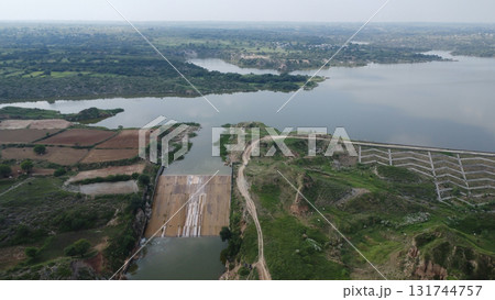 Aerial view of a dam and reservoir surrounded by lush green vegetation and farmland Aerial view of a dam and reservoir surrounded by lush green vegetation and farmland 131744757