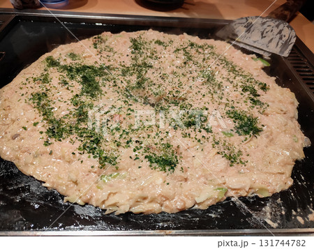 Traditional Japanese okonomiyaki being cooked on a teppan grill, showing delicious texture and authentic street food style. Traditional Japanese okonomiyaki being cooked on a teppan grill, showing delicious texture and authentic street food style. 131744782