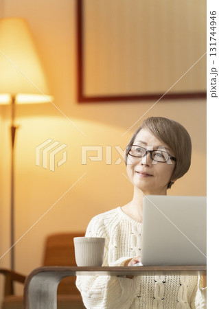 夜にリビングでノートパソコンで会話や読書をするシニア女性 131744946