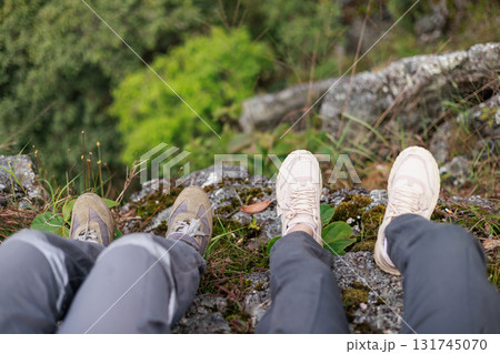 Close up of hiker resting on rocky cliff in hiking shoes, symbol of adventure, outdoor lifestyle, challenge, exploration, determination, nature journey and freedom in mountain travel. 131745070