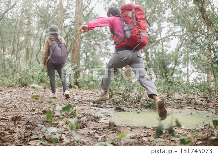 Hikers walking and jumping on forest trail with backpacks and trekking poles, symbol of adventure, teamwork, outdoor lifestyle, travel journey, energy, challenge and exploration in nature. 131745073
