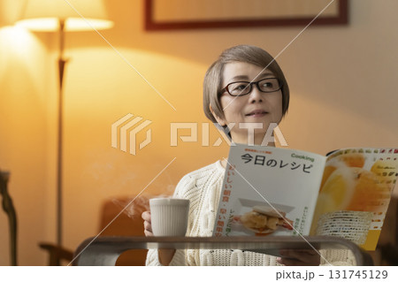 夜にリビングで料理のレシピ本を見るシニア女性 夜にリビングで料理のレシピ本を見るシニア女性 131745129