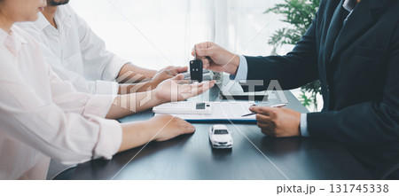 Panorama view of car dealer handing key and vehicle model to customer during contract signing, concept of auto loan, finance, leasing, insurance, purchase agreement and business success. auto loan. 131745338
