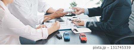 Panorama view of car loan agreement signing with dealer presenting vehicle model, customer using calculator at office desk, concept of auto finance, leasing, insurance and business contract. 131745339