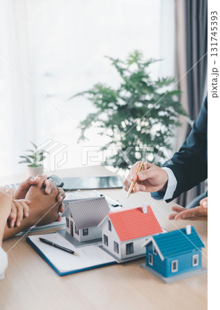 Close up of real estate agent showing small house model to client with calculator, contract paperwork on desk, concept of mortgage loan, home ownership, property investment agreement. mortgage loan Close up of real estate agent showing small house model to client with calculator, contract paperwork on desk, concept of mortgage loan, home ownership, property investment agreement. mortgage loan 131745393