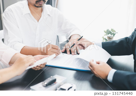 Businessman explaining car loan agreement with calculator, customer discussing auto finance deal at office desk with toy car and document, concept of vehicle loan, insurance or car leasing. car loan. 131745440