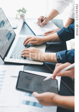 Business data analysis concept with colleagues reviewing financial report on laptop, pointing at chart with growth graph, teamwork discussing statistics, planning strategy and corporate success. 131745462