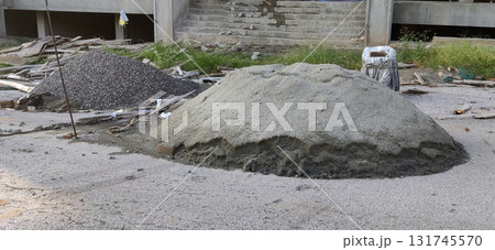 Wet cement heap and gravel pile with bucket on construction site during sunny daytime work preparation Wet cement heap and gravel pile with bucket on construction site during sunny daytime work preparation 131745570