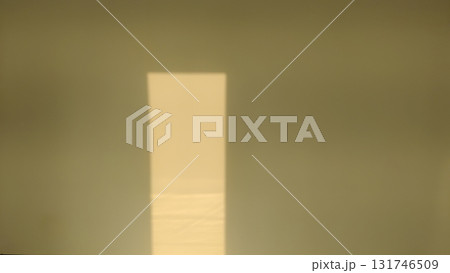 A rectangle of light shines on a wall in a simple and minimal scene shot 131746509