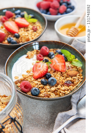 Granola bowls with berries, yogurt, nuts, and honey for breakfast 131748892