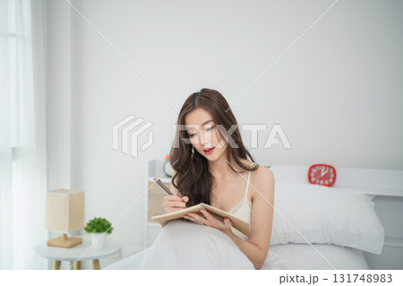 Young woman in light bedroom writing in notebook, cozy atmosphere, good lighting, natural inspiration, self-reflection, personal growth, lifestyle concept Young woman in light bedroom writing in notebook, cozy atmosphere, good lighting, natural inspiration, self-reflection, personal growth, lifestyle concept 131748983