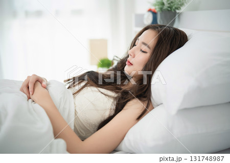 Young woman resting peacefully in a bright bedroom with soft natural light, feeling serene and relaxed while lying on a comfortable bed Young woman resting peacefully in a bright bedroom with soft natural light, feeling serene and relaxed while lying on a comfortable bed 131748987