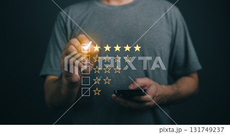 Close-up businessman hand Using Mobile Device to Rate Experience with Star Ratings on Dark Background, Customer Feedback Concept, Evaluation and Review Process 131749237