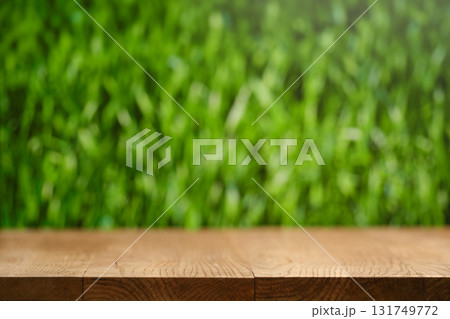 Wooden surface with blurred green grass background in a natural outdoor setting 131749772