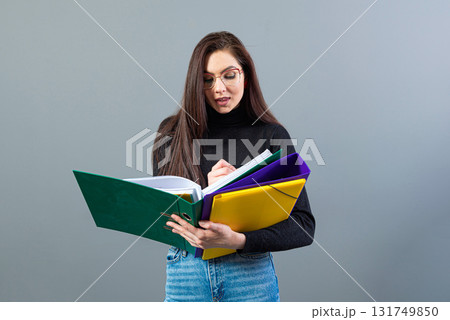 fashionable female holding a colorfuls folders with documents, isolated on dark background 131749850