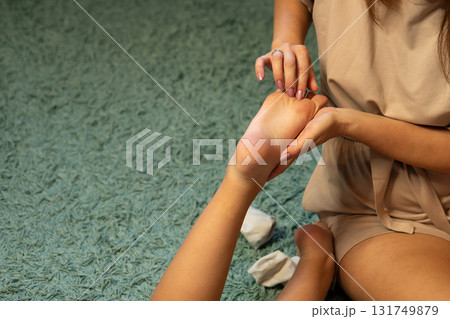 Parent massaging child's foot with careful pressure indoors Parent massaging child's foot with careful pressure indoors 131749879