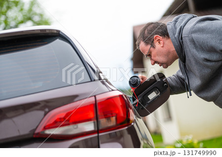 worried man looking at open car fuel tank, concept of rising fuel prices worried man looking at open car fuel tank, concept of rising fuel prices 131749990
