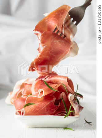 Prosciutto with rosemary on a white wooden table. Prosciutto with rosemary on a white wooden table. 131750665