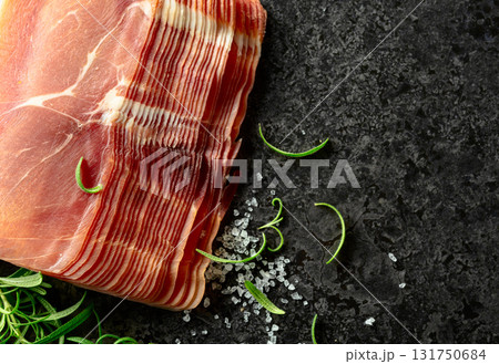 Sliced prosciutto and rosemary on a stone table. Sliced prosciutto and rosemary on a stone table. 131750684