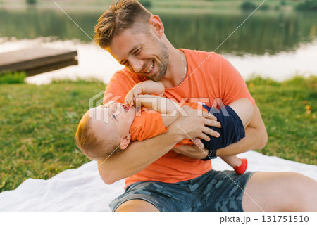 Father Playing With Baby On Picnic Blanket 131751510