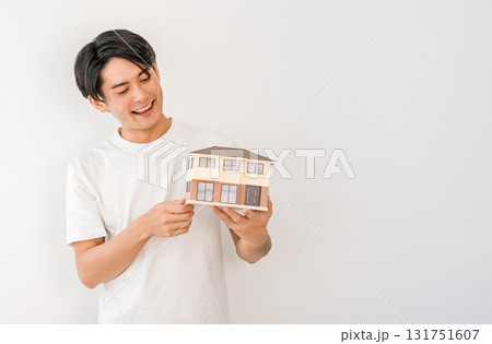 住宅模型を持つ笑顔の若いアジア人男性（マイホーム,一戸建て,家づくり） 131751607