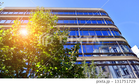 Glass office building surrounded with green trees.  Eco-friendly office building. Sustainable architecture of city reducing heat carbon dioxide modern city environment. Glass office building surrounded with green trees.  Eco-friendly office building. Sustainable architecture of city reducing heat carbon dioxide modern city environment. 131751729