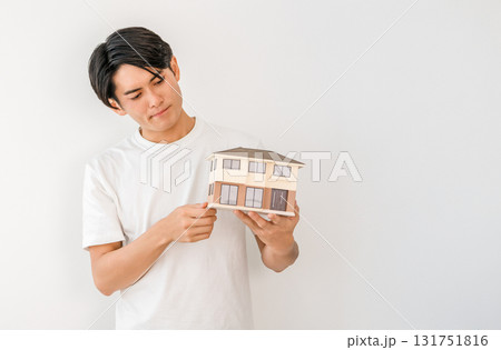 住宅模型を持つ若いアジア人男性（マイホーム,一戸建て,家づくり,失敗,後悔,トラブル） 131751816