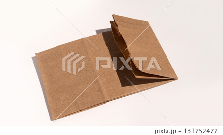 Brown kraft paper bag lying flat on neutral background with sunlight Brown kraft paper bag lying flat on neutral background with sunlight 131752477