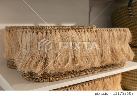 Handwoven fringe basket on white shelf with fiber texture and natural design 131752508