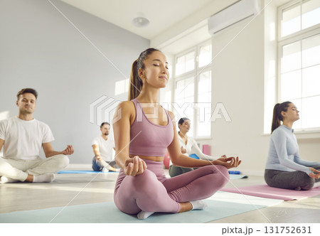 Woman Meditating in Lotus Pose Amidst Yoga Group 131752631