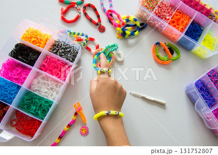 Child creating colorful loom band bracelets with assortment of rubber bands Child creating colorful loom band bracelets with assortment of rubber bands 131752807