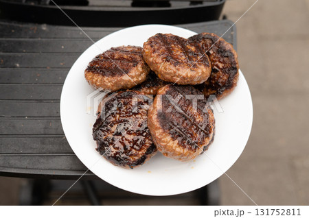 Grilled beef burgers on white plate outdoors Grilled beef burgers on white plate outdoors 131752811