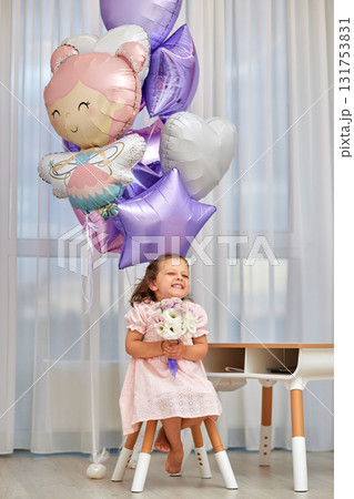 Cute little child girl in pink dress with flowers and pink purple balloons. Birthday concept. Cute little child girl in pink dress with flowers and pink purple balloons. Birthday concept. 131753831